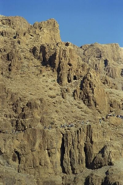Tourists walking through rocky landscape in Wadi Rumdan, south of Judea
