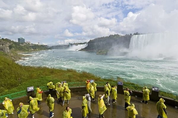 Many tourists in yellow raincoats in the spray of the Horseshoe Falls waterfall whilst on the Journey under the Falls tour, Niagara Falls, Ontario, Canada