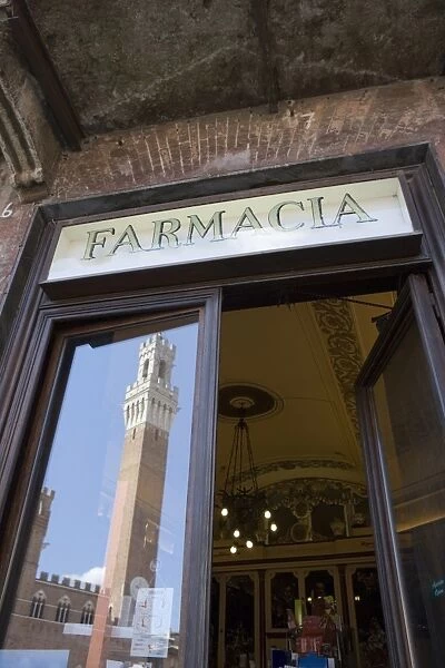 The tower of Palazzo Pubblico reflected in Farmacia window, Piazza del Campo