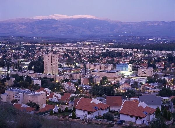 The town of Kiriat Shmona at dusk in the Upper Galilee area, with snow covered Mount Hermon in background, Israel