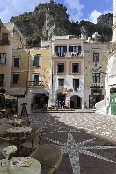 Town square with restaurant tables and colourful buildings, star shaped paving, Atrani