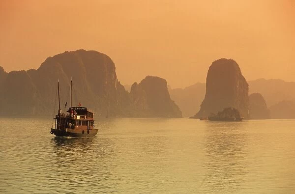 Traditional boat sailing through limestone archipelago at sunset, Ha Long Bay, UNESCO World Heritage Site, Northeast, Vietnam, Indochina, Southeast Asia, Asia