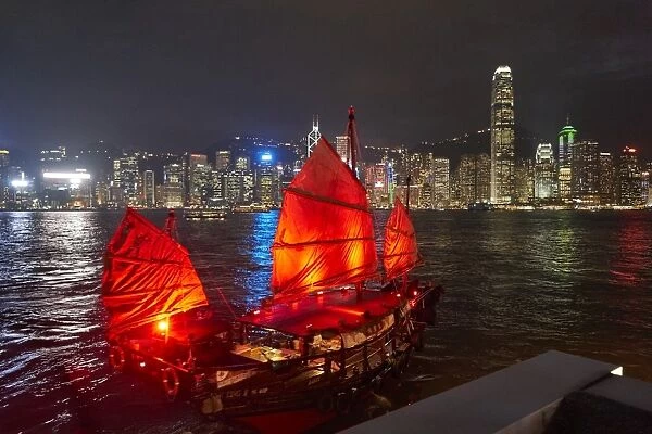 Traditional Chinese junk boat for tourists on Victoria Harbour illuminated at night