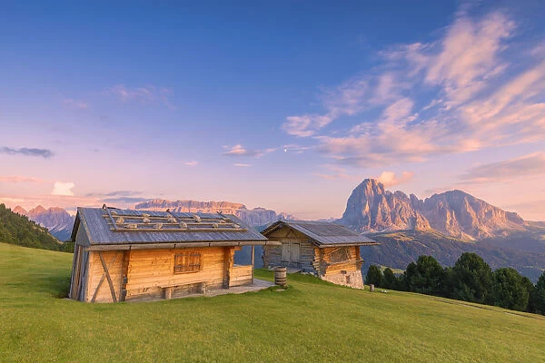 Traditional huts at sunset with Sassolungo and Sella Group in the background. Gardena Valley