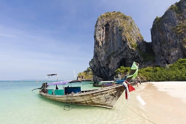 Traditional Longtail boats moored by Phra Nanag Beach with limestone cliffs in the background