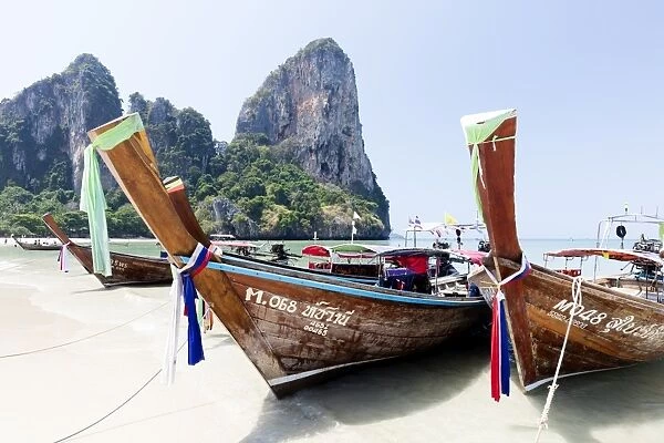Traditional Longtail boats moored by Railay Beach with limestone cliffs in the background