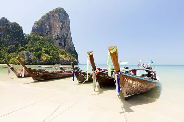 Traditional Longtail boats moored by Railay Beach with limestone cliffs in the background