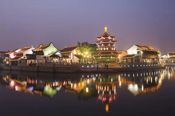 Traditional old riverside houses and pagoda illuminated at night in Shantang water town