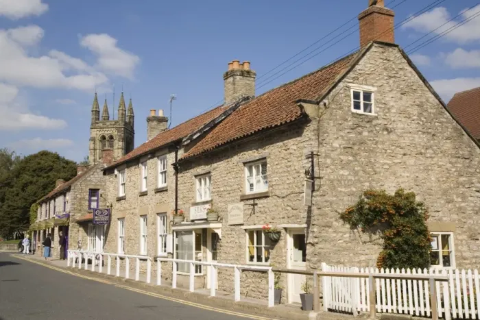Framed Print : Traditional sandstone cottages and shops with tower of All Saints Church Framed Print : Traditional sandstone cottages and shops with tower of All Saints Church