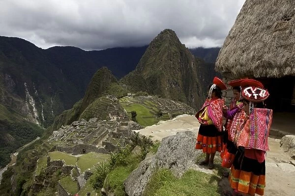 Traditionally dressed children looking over the ruins of the Inca city of Machu Picchu, UNESCO World Heritage Site, Vilcabamba Mountains, Peru, South America