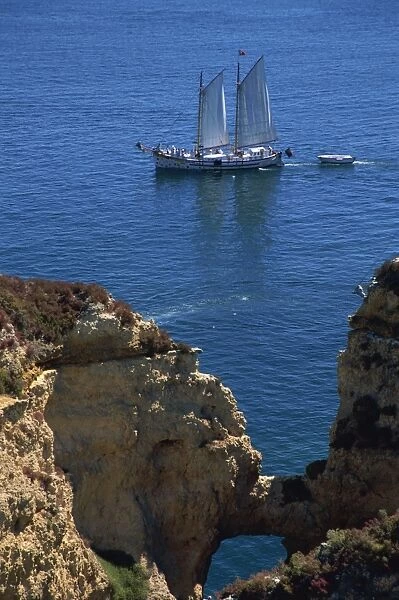 Tranquil scene of sailing boat offshore from rock formations