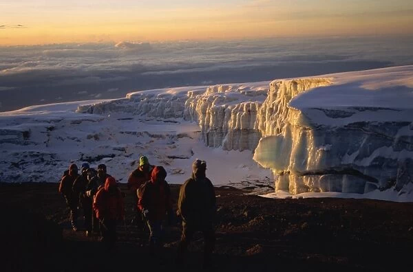 Trekkers and glacier at sunrise on summit of Kibo, 5895m, Kilimanjaro National Park