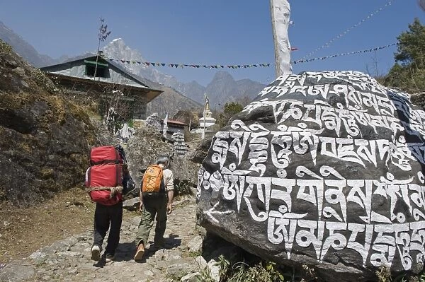 Trekkers walking past a mani stone, Solu Khumbu Everest Region, Sagarmatha National Park