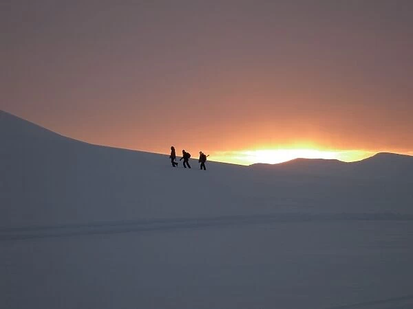Trekking or hiking in winter snow in February as the sun rises over the mountains after the four month long winter dark period, Svalbard, Arctic, Norway, Scandinavia, Europe