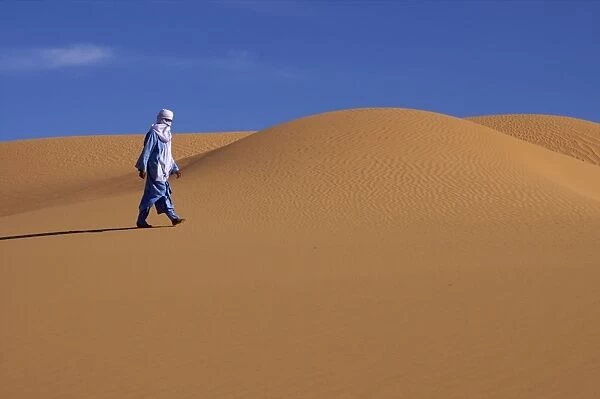 A Tuareg walking on a dune of the erg of Uan Kaza in the Fezzan desert