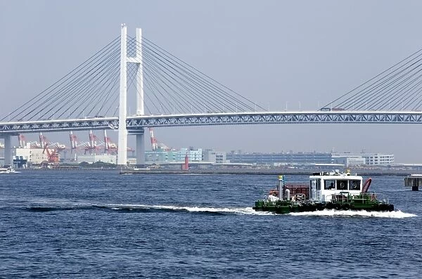 Tug boat passing by the Yokohama Bay Bridge which spans the Tokyo Bay in Yokohama