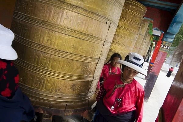 Turning large prayer wheels in temple, Yushu, Qinghai, China, Asia