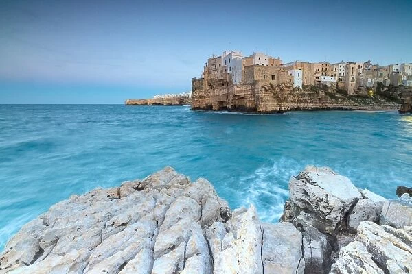 Turquoise sea at dusk framed by the old town perched on the rocks, Polignano a Mare