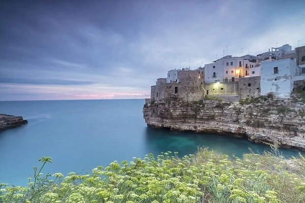 Turquoise sea at sunrise framed by the old town perched on the rocks, Polignano a Mare