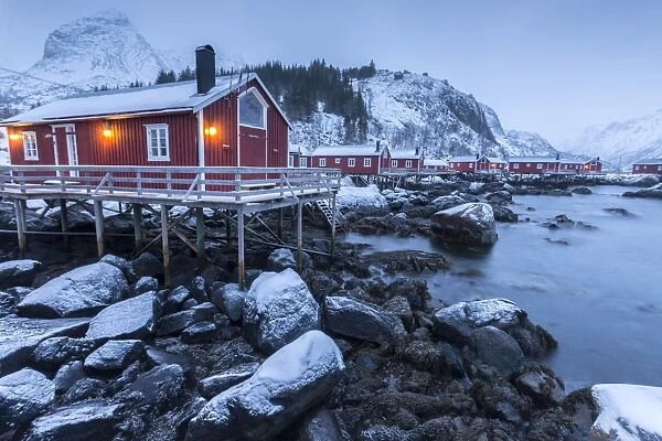 Typical fishermen houses called rorbu in the snowy landscape at dusk, Nusfjord, Nordland County