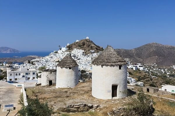A typical Greek village perched on a rock with white and blue houses and quaint windmills
