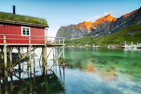Typical house of fishermen called Rorbu lit up by midnight sun, Reine, Nordland county