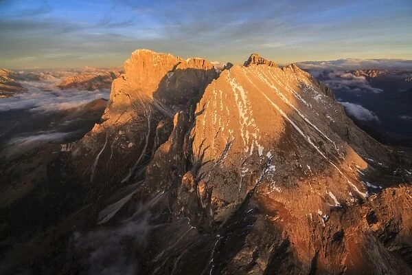 The unmistakable profiles of Sassopiatto (Plattkofel) and Sassolungo (Langkofel) lit by the warm light of the sunset, South Tyrol, Dolomites, Italy, Europe