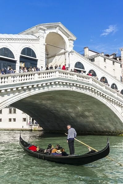 Venice gondola with tourists going under the Rialto bridge (Ponte del Rialto), Grand Canal