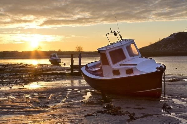 View towards the Aln Estuary during a stunning winter sunrise from the beach at low tide with a fishing boat in the foreground, Alnmouth, near Alnwick, Northumberland, England, United Kingdom, Europe