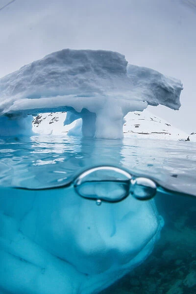 Above and below view of an arch formed in an iceberg at Cuverville Island, Ererra Channel
