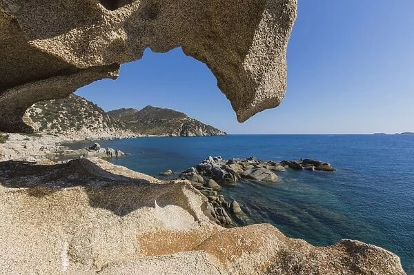 View of the blue sea from a natural sea cave of rocks shaped by wind, Punta Molentis