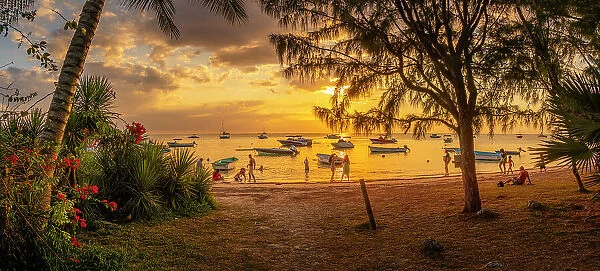 View of boats and people on Mon Choisy Public Beach at sunset, Mauritius, Indian Ocean, Africa