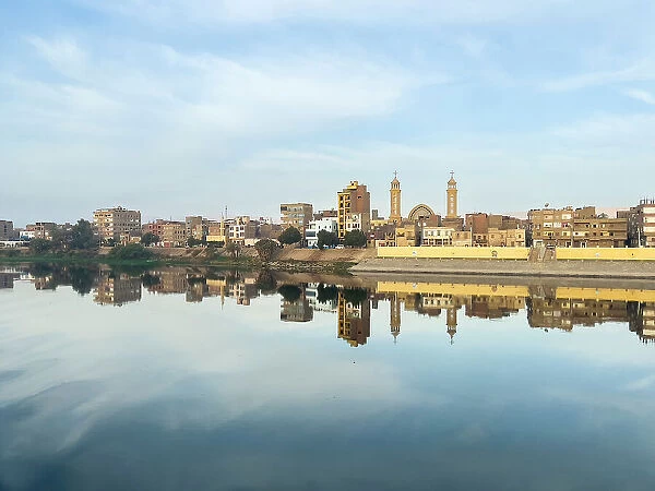 View of buildings reflected in the water on the Nile River, Dendera, Egypt, North Africa, Africa
