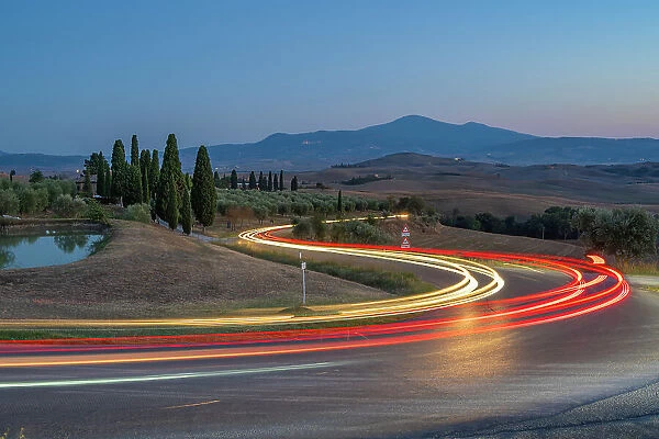 View of car trail lights in Tuscan landscape near Pienza at dusk, Pienza, Province of Siena, Tuscany, Italy, Europe