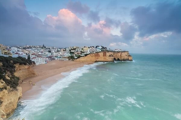 View of Carvoeiro village surrounded by sandy beach and turquoise sea at sunset, Lagoa Municipality