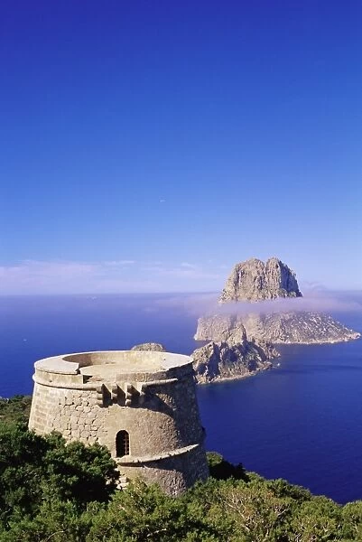 View of a defence tower and rocky islet of Es Vedra
