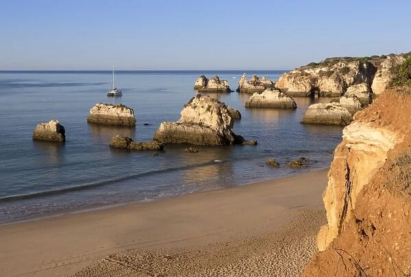 View of the fine sandy beach bathed by the blue ocean at dawn, Praia do Alemao, Portimao