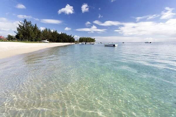 View along Flic en Flac Beach showing the clear shallows of the Indian Ocean, blue sky and white sand, on the west coast of Mauritius, Indian Ocean, Africa