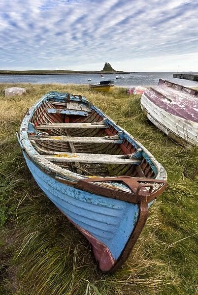 View towards Lindisfarne Castle with an old blue and red fishing boat in the foreground, Lindisfarne (Holy Island), Northumberland, England, United Kingdom, Europe