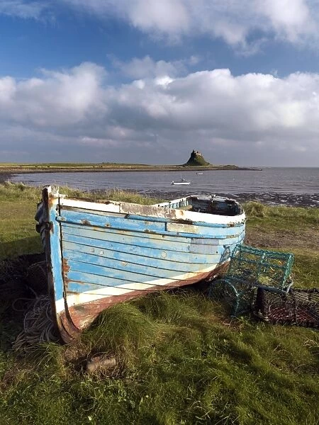 View towards Lindisfarne Castle with old fishing coble and lobster pots in the foreground
