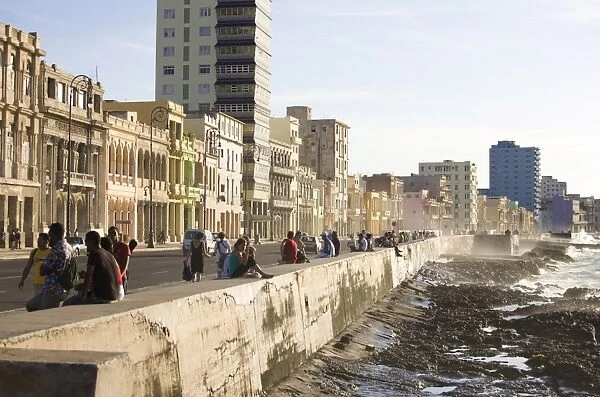 View along The Malecon showing people sitting on the seawall enjoying the evening sunshine