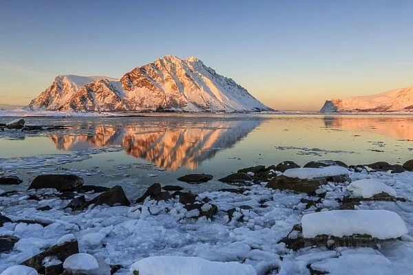 View of the mountains of Gymsoya (Gimsoya) from Smorten reflected in the clear partially frozen sea