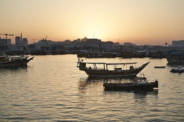 View from the Museum of Islamic Arts towards the old part of Doha and the dhows moored in the Harbour, at sunset, Doha, Qatar, Middle East