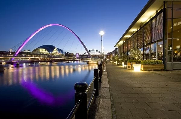 View along Newcastle Quayside at night showing the River Tyne, the floodlit Gateshead Millennium Bridge, the Arched Bridge and the Sage Gateshead, Newcastle-upon-Tyne, Tyne and Wear, England, United