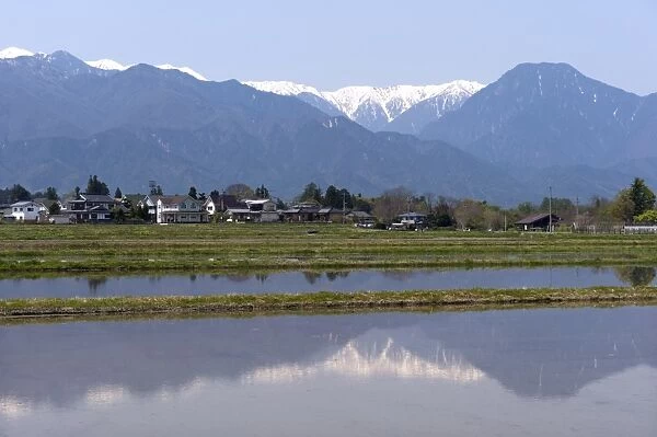 View of the Northern Alps reflected in a flooded rice paddy, Nagano Prefecture, Japan