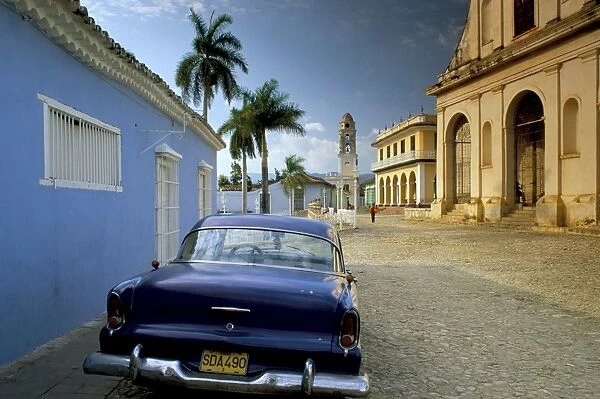View across Plaza Mayor with old American car parked on cobbles, Trinidad
