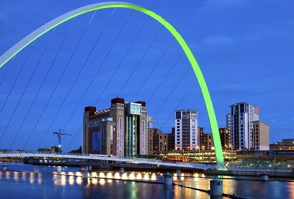 View along the Quayside at night showing the Baltic Centre for Contemporary Arts framed by the floodlit Gateshead Millennium Bridge, Newcastle-upon-Tyne, Tyne and Wear, England, United
