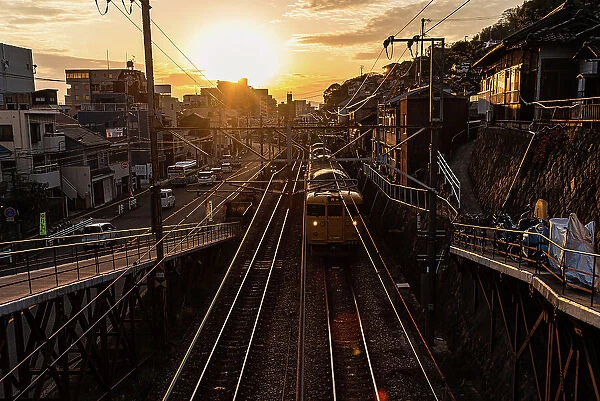 View from a railway bridge with a yellow Japanese train approaching during sunset, Onomichi, Honshu, Japan, Asia