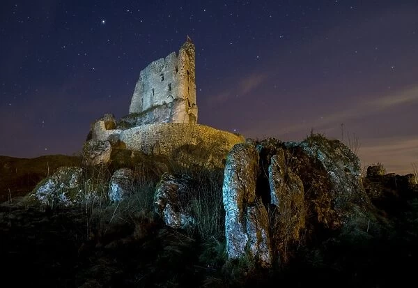 View of rocks and Mirow Castle ruins illuminated at night, Polish Jura, Poland, Europe