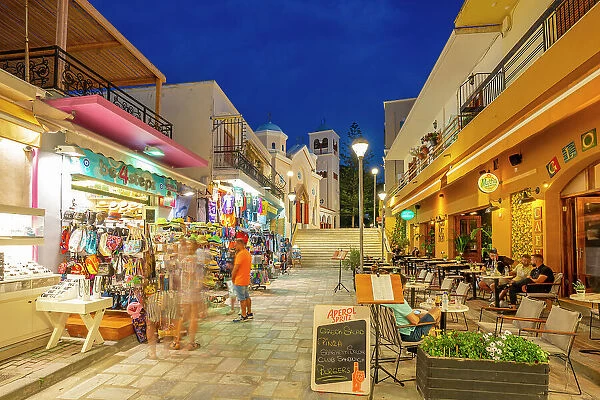 View of shops and restaurants with Church of Agia Paraskevi in the background in Kos Town at dusk, Kos, Dodecanese, Greek Islands, Greece, Europe